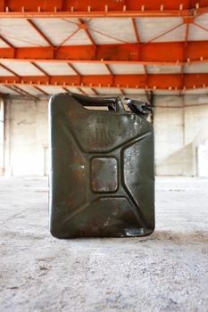 a green jerry can on concrete floer.