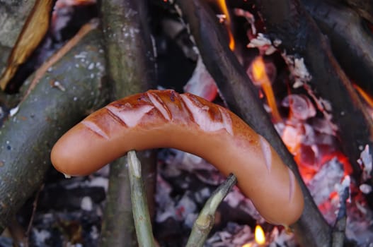 a sausage grilled on a camp fire