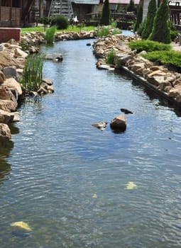 artificial river with rocks and green grass on particular garden