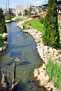 artificial river with rocks and green grass on particular garden