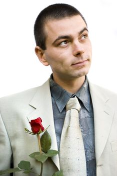 young romantic business man holding red rose in hand looking up