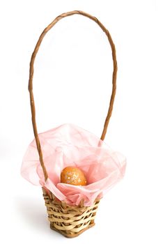 orange colored easter egg in wooden basket with pink ribbon