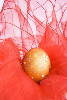 orange easter egg with red ribbon veil in basket