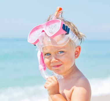 A cute little boy wearing a mask for diving background of the sea