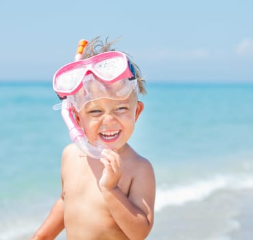 A cute little boy wearing a mask for diving background of the sea