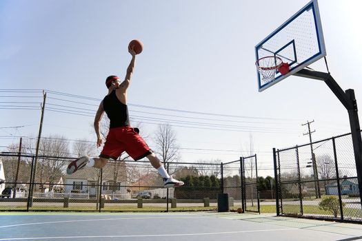 A young basketball player flying towards the rim for a slam dunk.