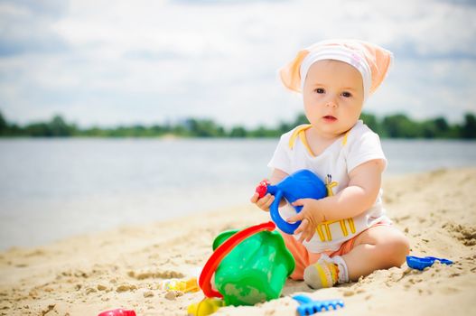 cute baby girl playing on the beach with sand.