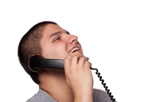 A young man listens on the telephone with a huge happy smile on his face.