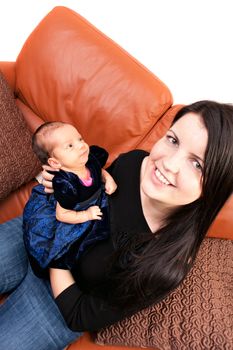 A newborn baby being held in the arms of her mother while seated on the sofa.