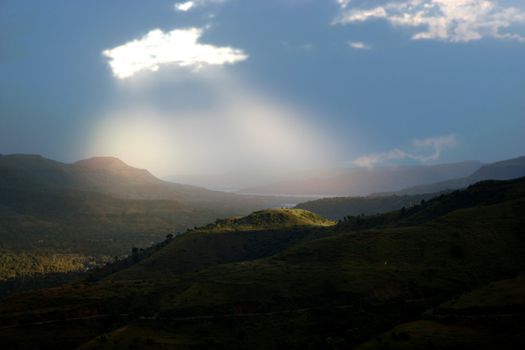 A ray of light falling from a hole in the clouds appearing like blessing from the heavens.