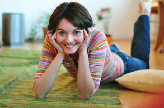 Portrait of happy young woman resting on floor at home