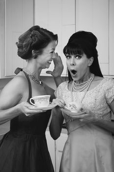 Pretty retro Caucasian women gossiping over coffee in kitchen