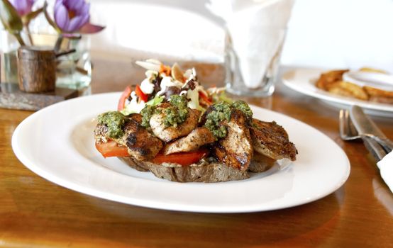 horizontal landscape of plated main course of pepper grilled chicken tomato salad mayo on bed of tofu table accessories mustard pot white plate cutlery home fries water glass crop space copy area