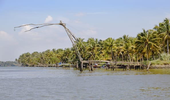 Landscape fishing apparatus in Kerala backwaters lakes, horizontal crop space copy space blue sky reflections on the water surface