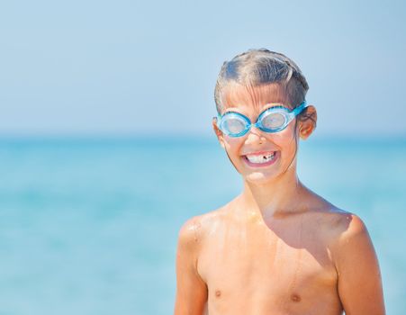 Portrait of a cute girl close-up of swimming goggles in the background of the sea