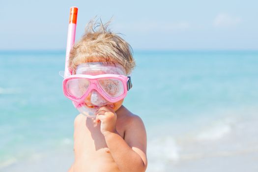 A cute little boy wearing a mask for diving background of the sea