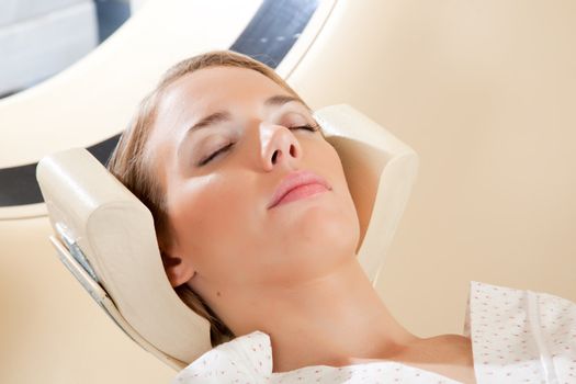 A relaxed woman with eyes closed ready for a CT scan