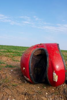 Broken red helmet lying on a field