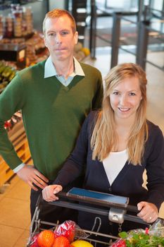 High angle view of smiling woman looking at camera while shopping with man in store