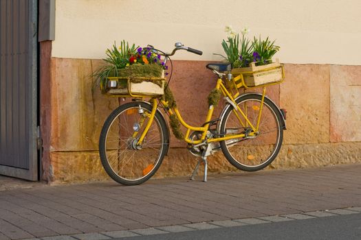 Flowers on a yellow bicycle on a house wall