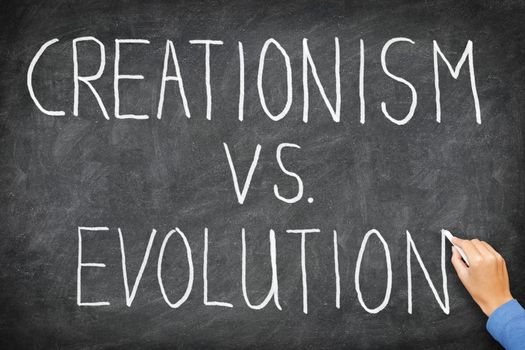 Creationism vs evolution. Religion and education concept. Hand writing on blackboard.