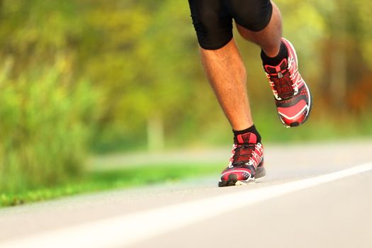 Runner - running shoes closeup. Man jogging and training for marathon outdoor in park.