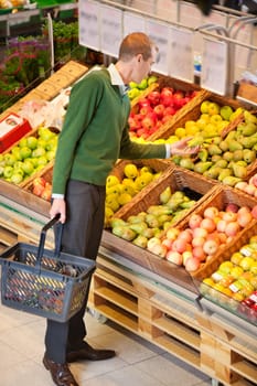 Adult man examining fruits to buy in shopping centre