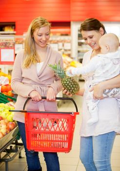 Two friends in grocery store buying groceries with baby