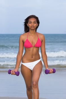 Caribbean fitness model posing with two dumbbells