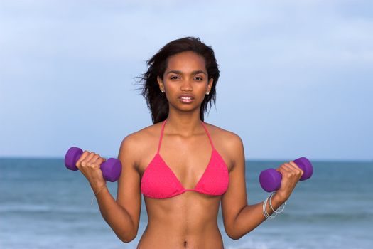Caribbean fitness model doing dumbbell exercises