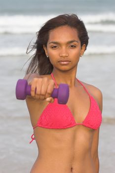 Ethnic Fitness Model holding up a dumbbell