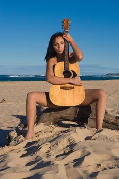 Nude girl with a guitar at the beach