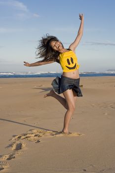 Girl with "happy Face" top running at the beach