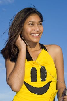 Girl with smiley face top listening to music on headphones