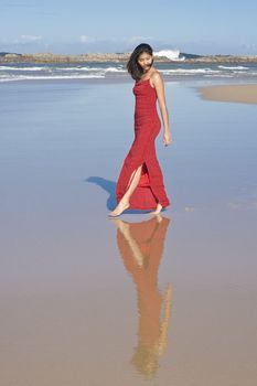 Lady in red dress walking at the beach