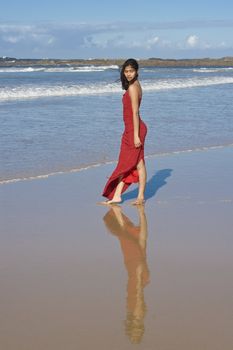 Beautiful girl in red dress on the beach
