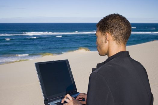 Young professional working on a laptop at the beach