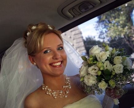 Beautiful the bride with a bouquet in the automobile