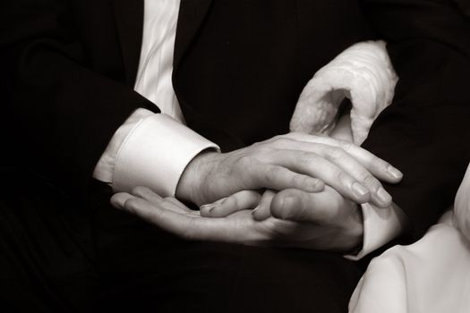 Female hands in man's hands on a dark background. b/w+sepia