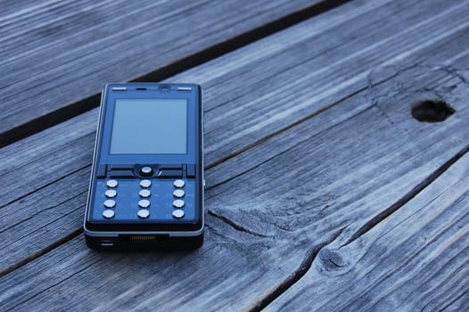 a black mobile phone lying on the bench