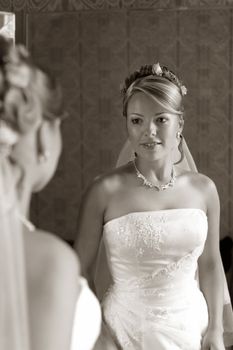The beautiful bride looks at itself in a mirror. b/w+sepia
