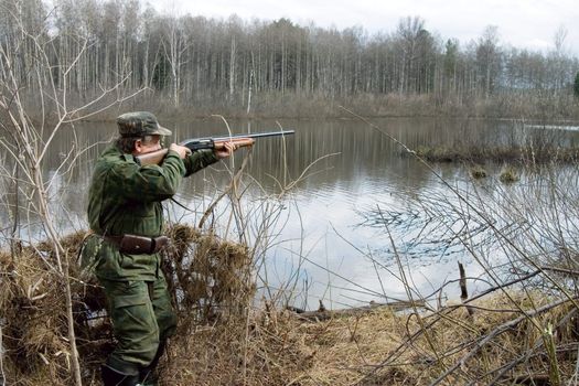 The hunter in a tent aims from a gun