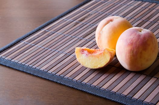 Two juicy peaches on a bamboo napkin