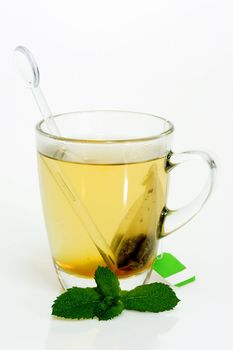 Glass of hot tea with peppermint on bright background