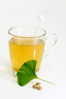 Ginkgo Biloba extract pills and fresh Ginkgo Biloba leaves with a glass of tea. 
