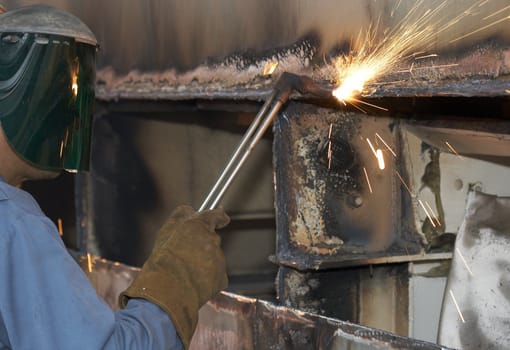 a welder working a torch at shipyard