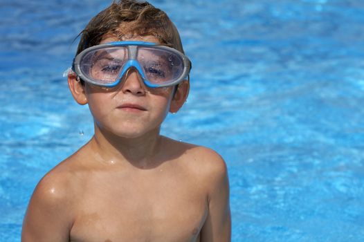 a young boy in pool with goggles on