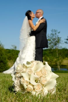 Wedding bouquet in focus and couple in blur