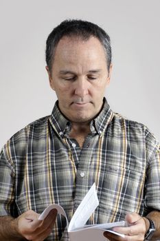 Middle-aged man reading an instruction manual looking puzzled.