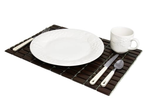 Dinner plate, white textured China with grapes and tomatoes design over a dark wood place mat shot diagonal